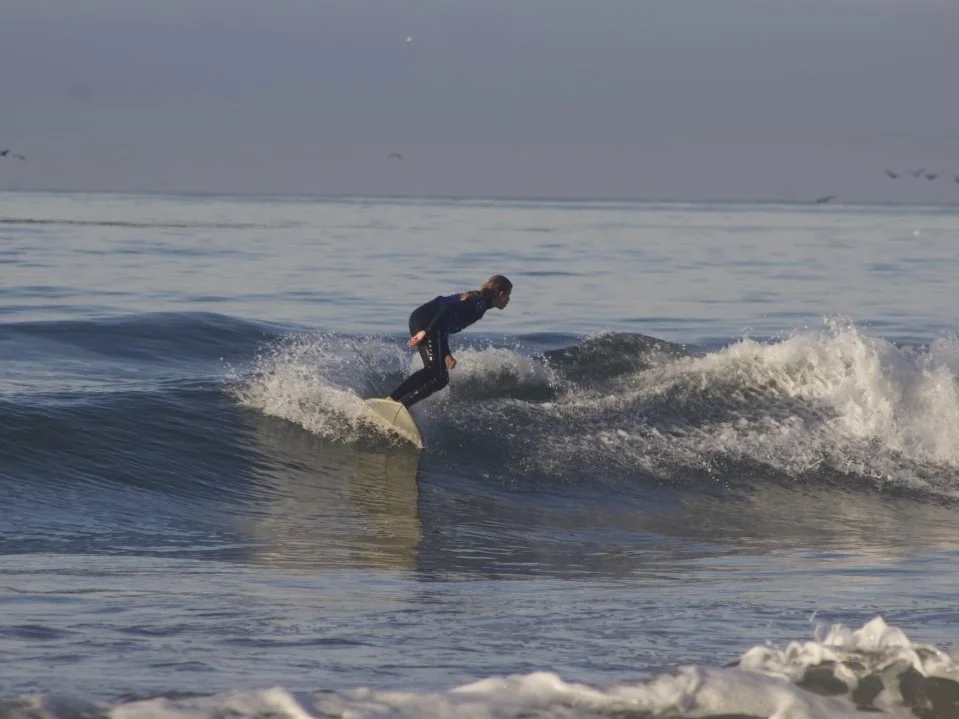 A person surfing on a small wave in the ocean during daylight.