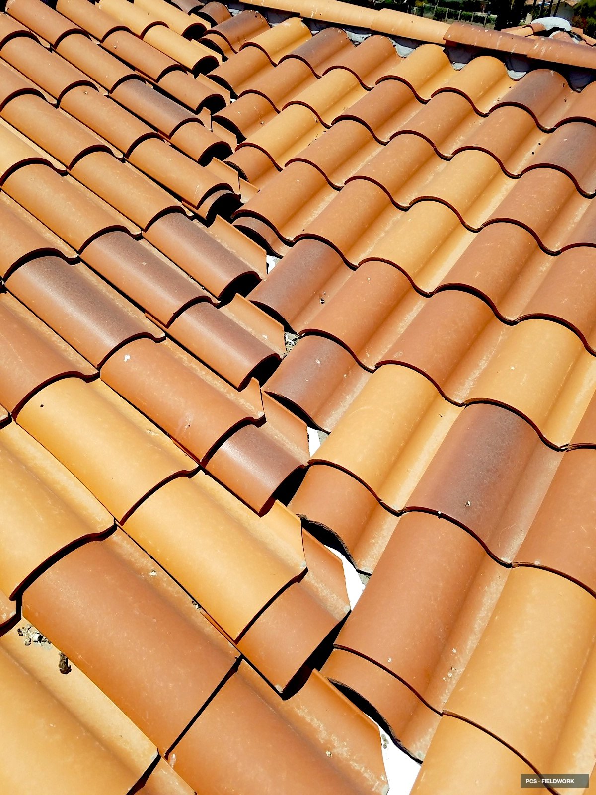 Close-up view of a roof with orange clay tiles arranged in a repeating pattern.