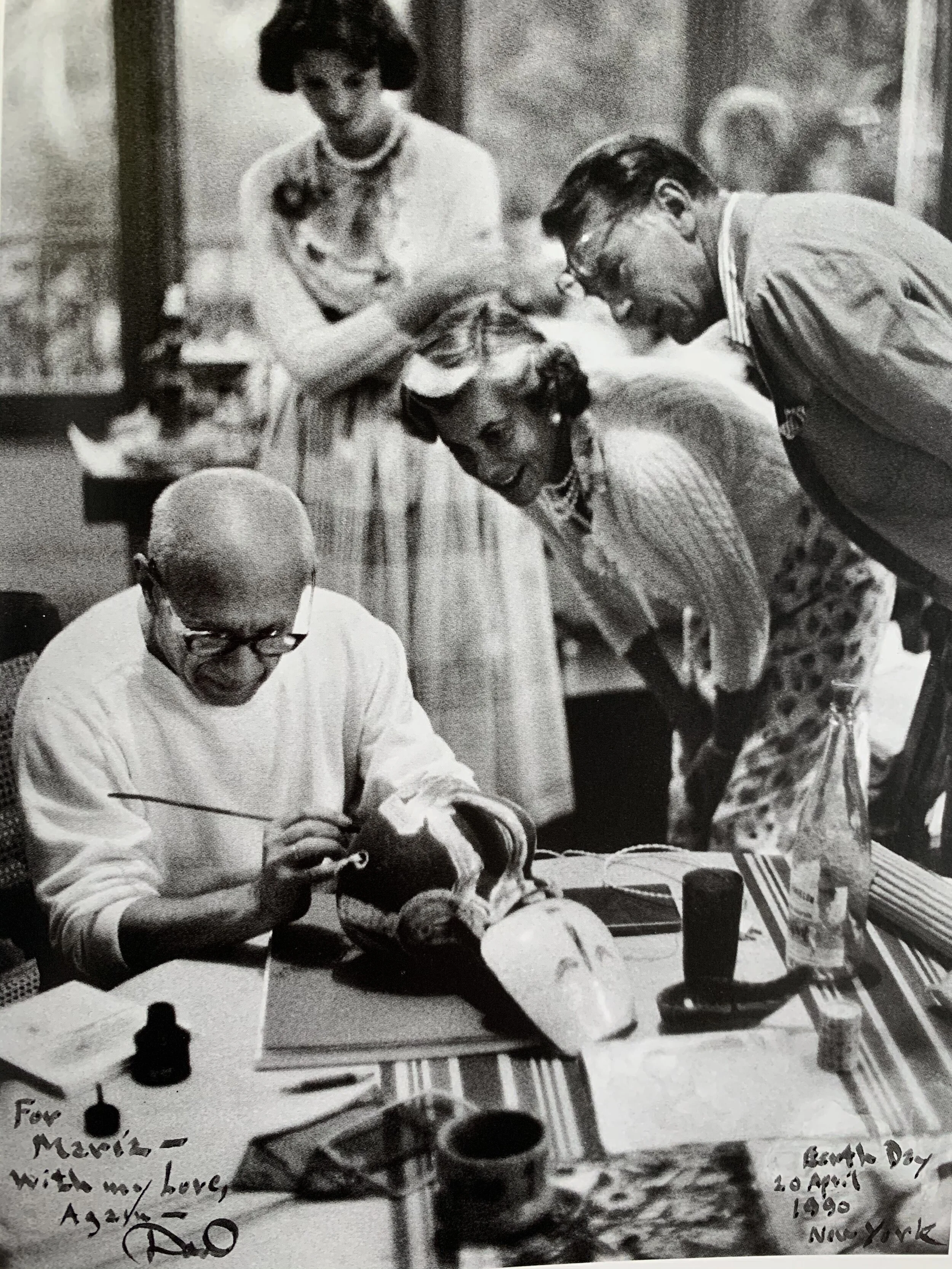 A black-and-white photo of a veterinarian examining a dog's mouth while four people, including a man and a woman, look on and smile. The photo is inscribed with a message for Marvie, dated April 20, 1990, in New York. Gary Cooper. Picasso.