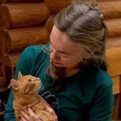 Woman holding and looking at an orange tabby cat