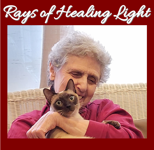 An elderly woman with gray curly hair is hugging a Siamese cat, both smiling. The background shows a wicker chair and a white curtain, with red text at the top reading "Rays of Healing Light."