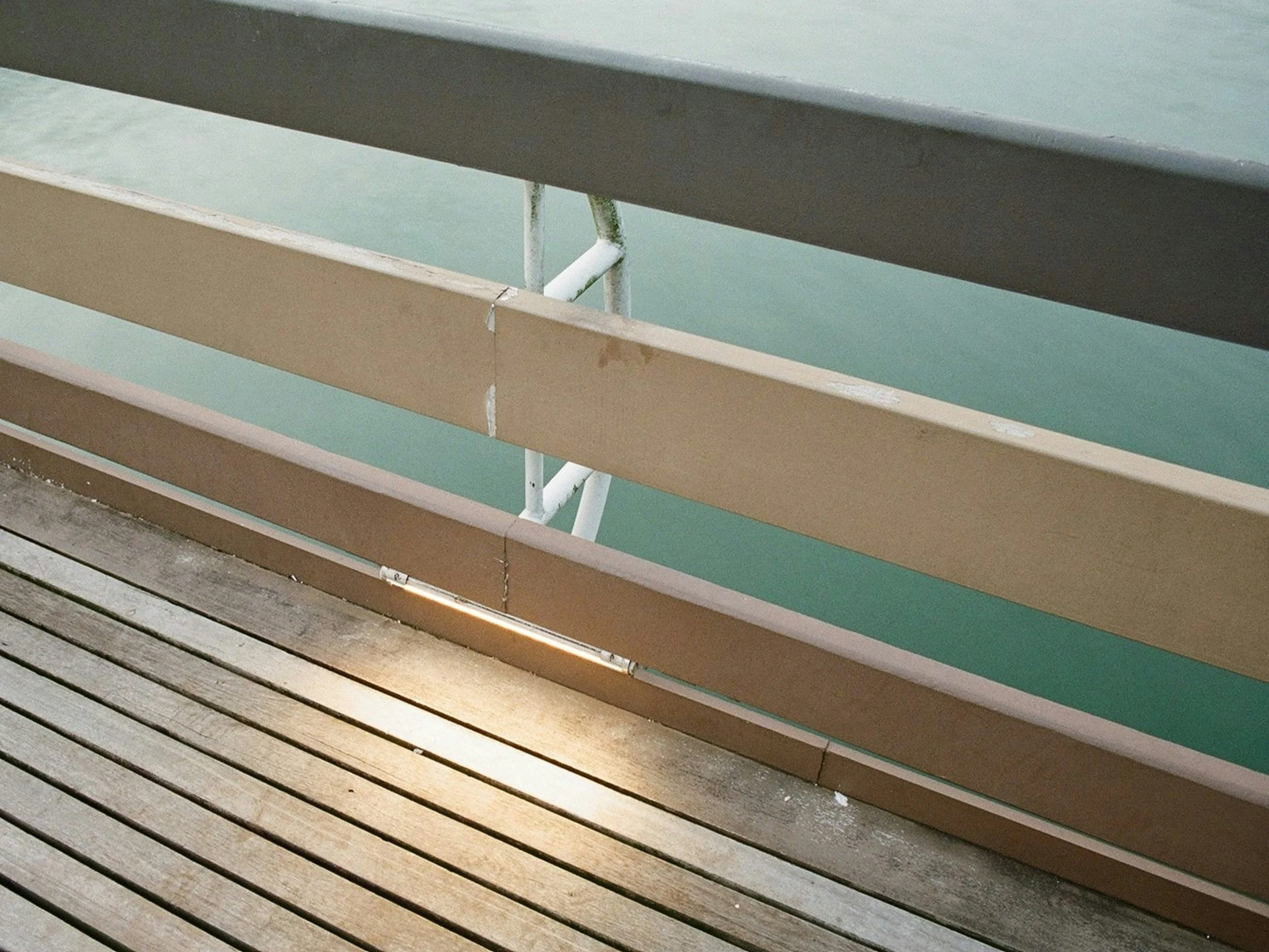 Close-up of wooden and metal railings on a balcony with water visible in the background.