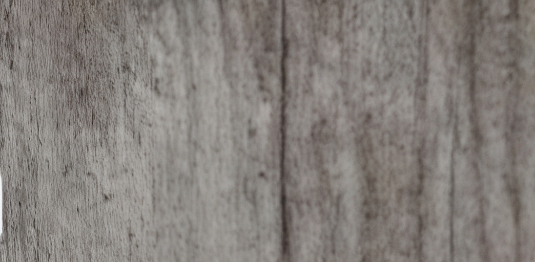 Close-up image of a textured wooden surface with visible grain and a vertical seam.