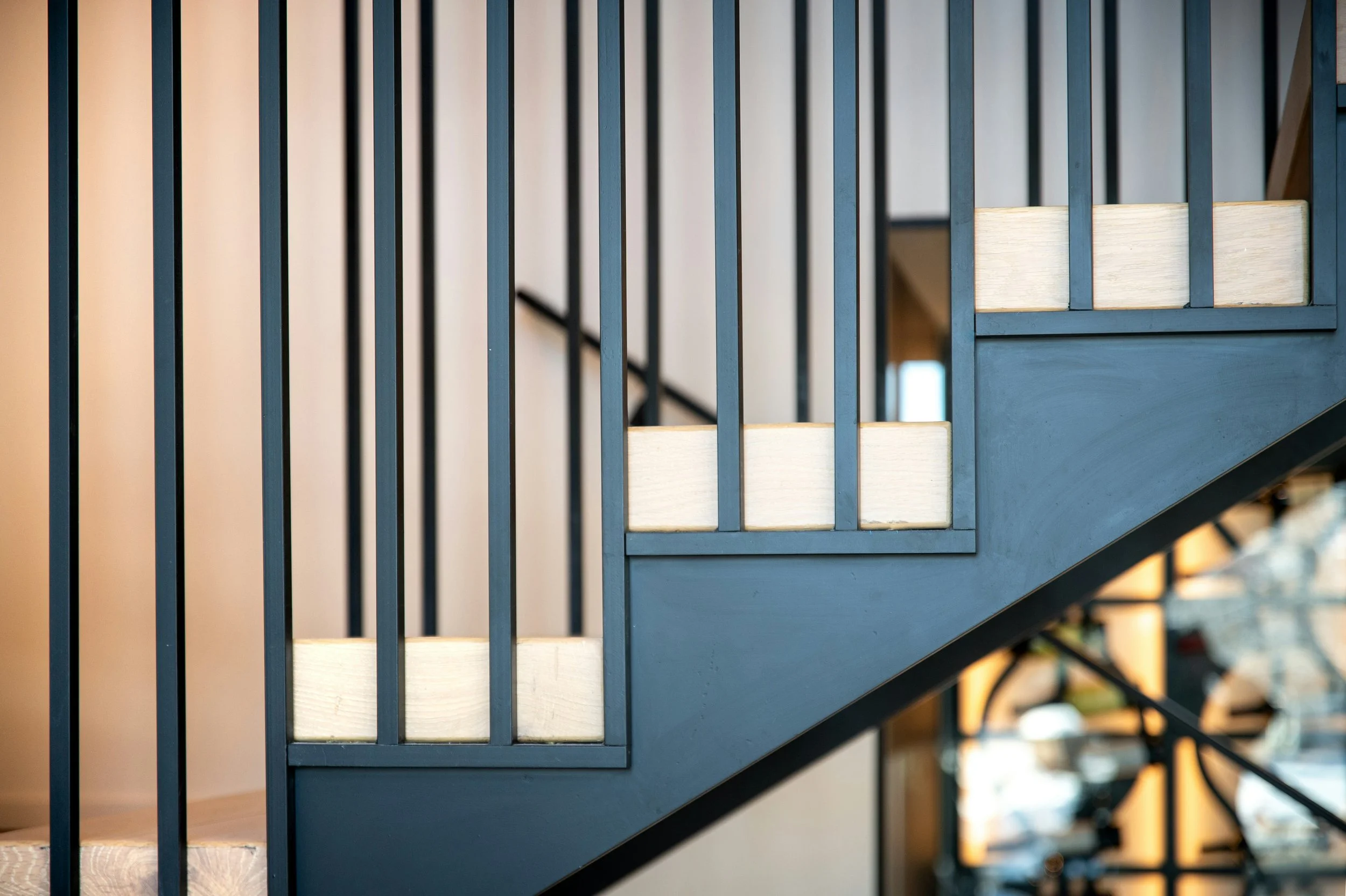 A staircase with black metal vertical bars on the side and light-colored wooden steps.