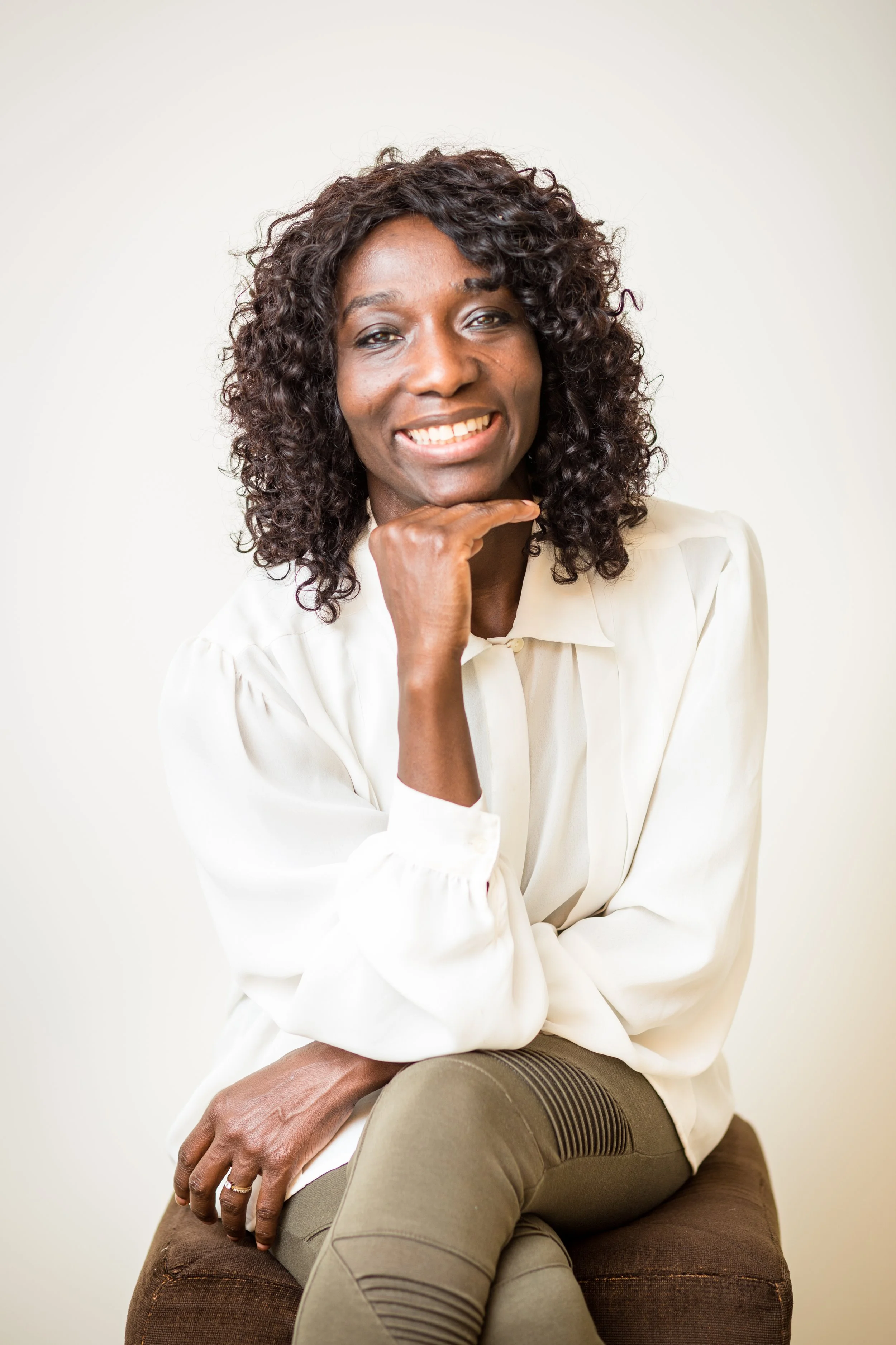 Jamila Gubbels, Registered Nurse and Death Doula, smiling in a relaxed portrait on the About page of Tender Presence.