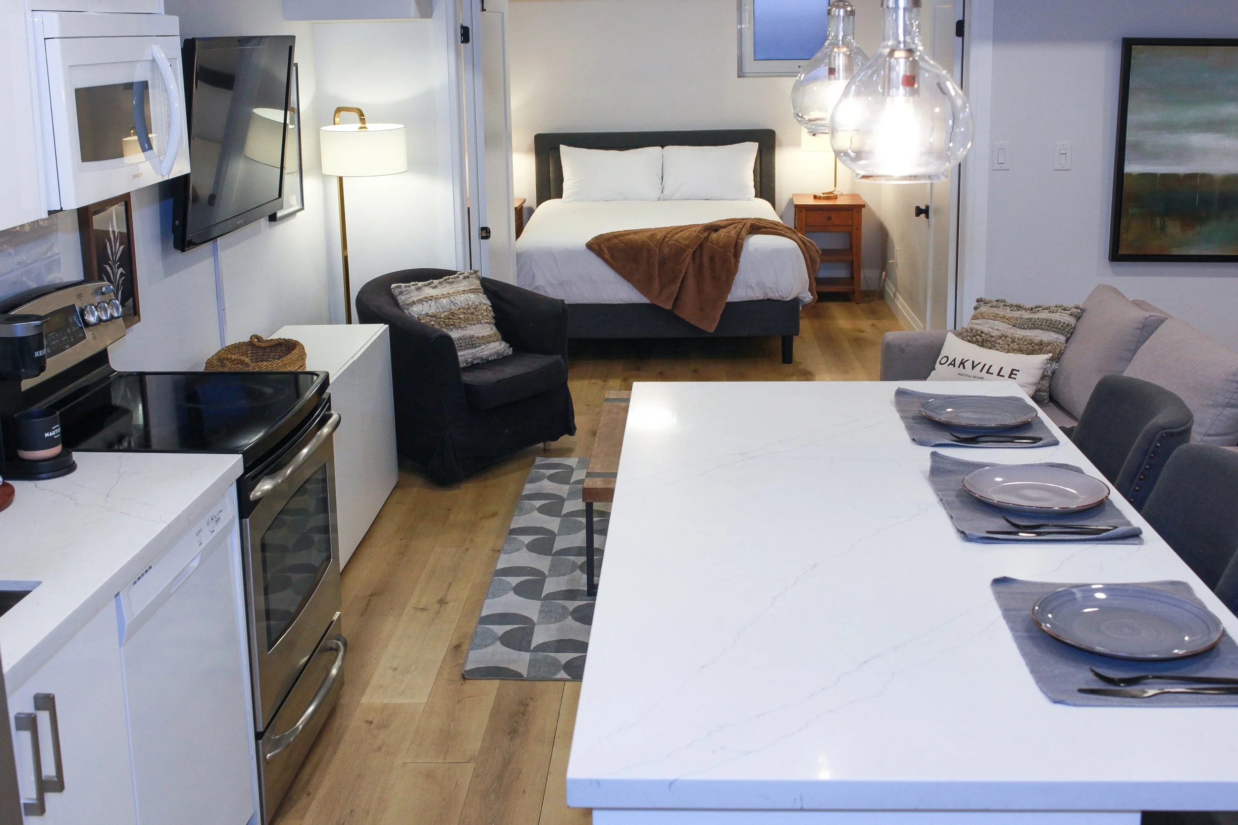 Open-concept living space and kitchen with a dining table, a bed in the background, and modern decor.