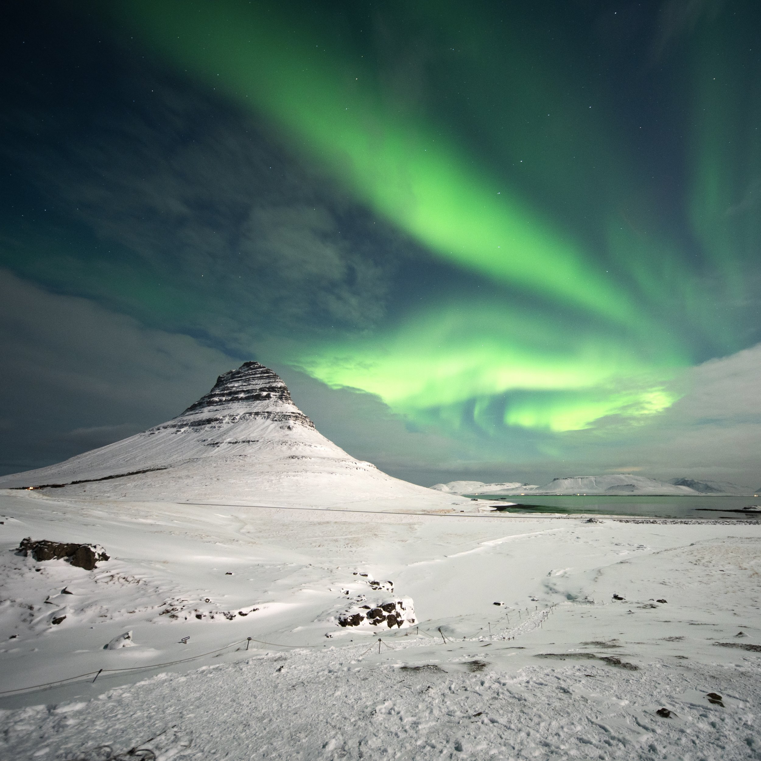Snow-covered mountain with Northern Lights in the sky.