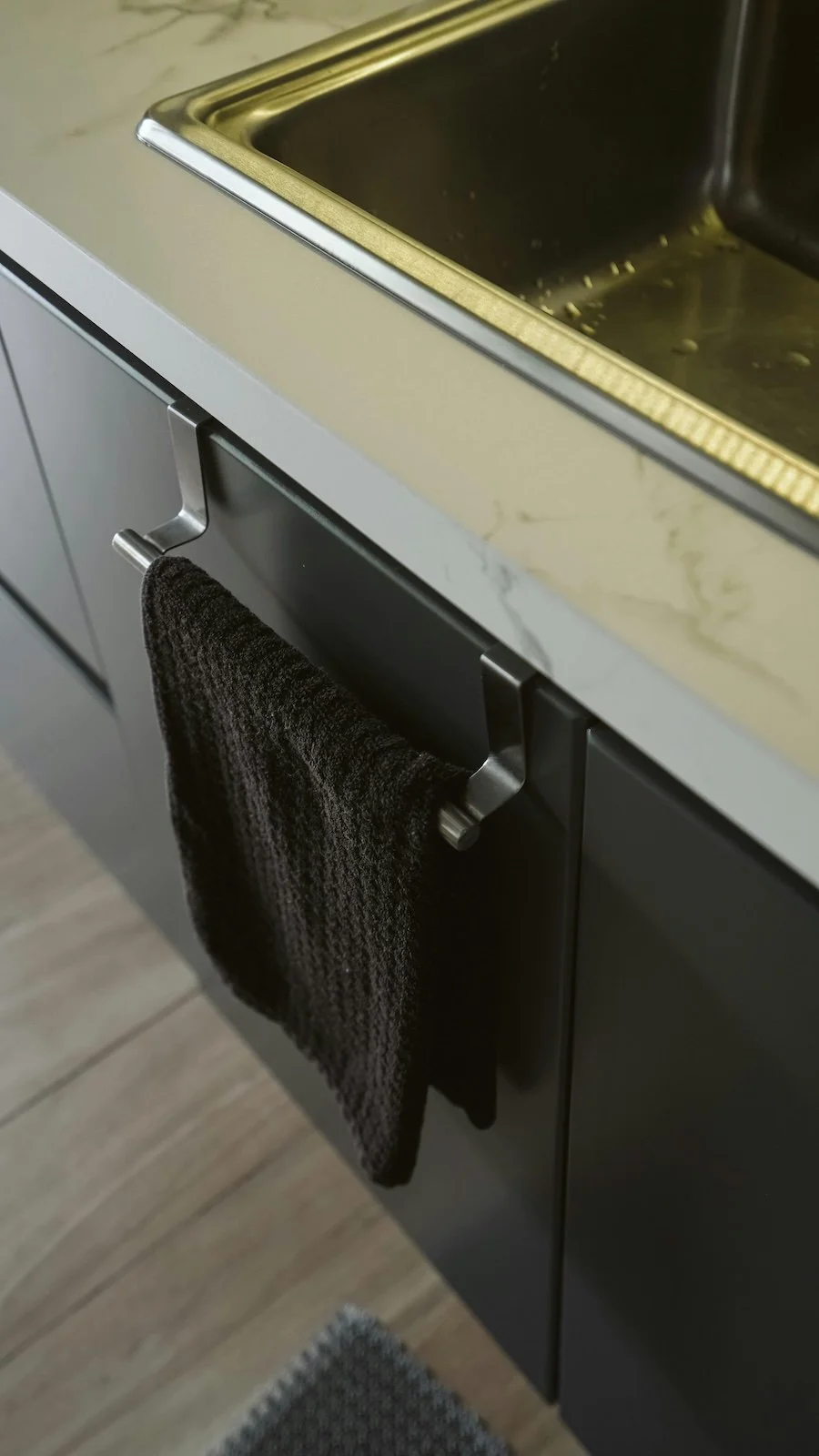 Closet vuelto con una toalla negra colgada en un gancho de metal en una cocina moderna.