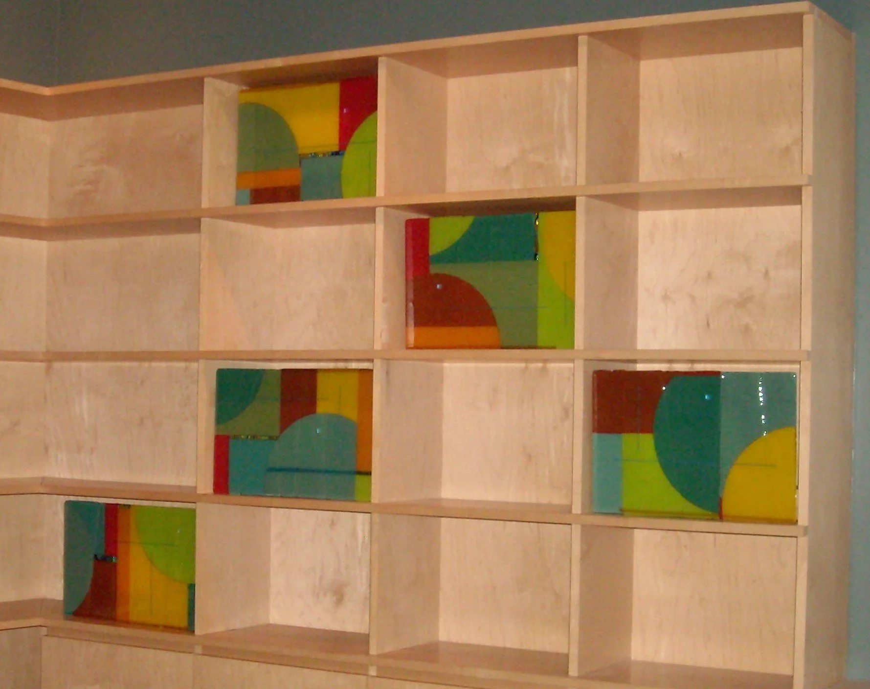 Yolanda Adra Designs:  Opalescent and dichroic fused glass embedded in a wooden shelving unit. Each panel:  10H x 16W. 