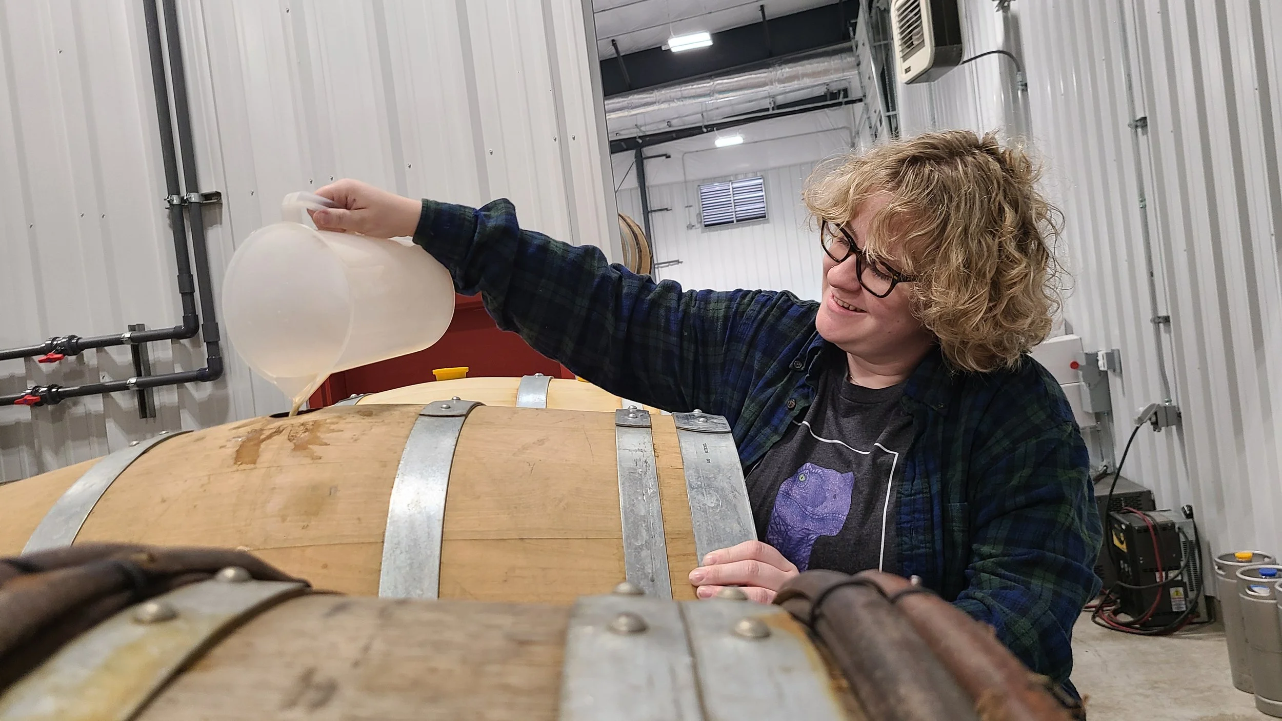 Enologist topping white barrel with wine