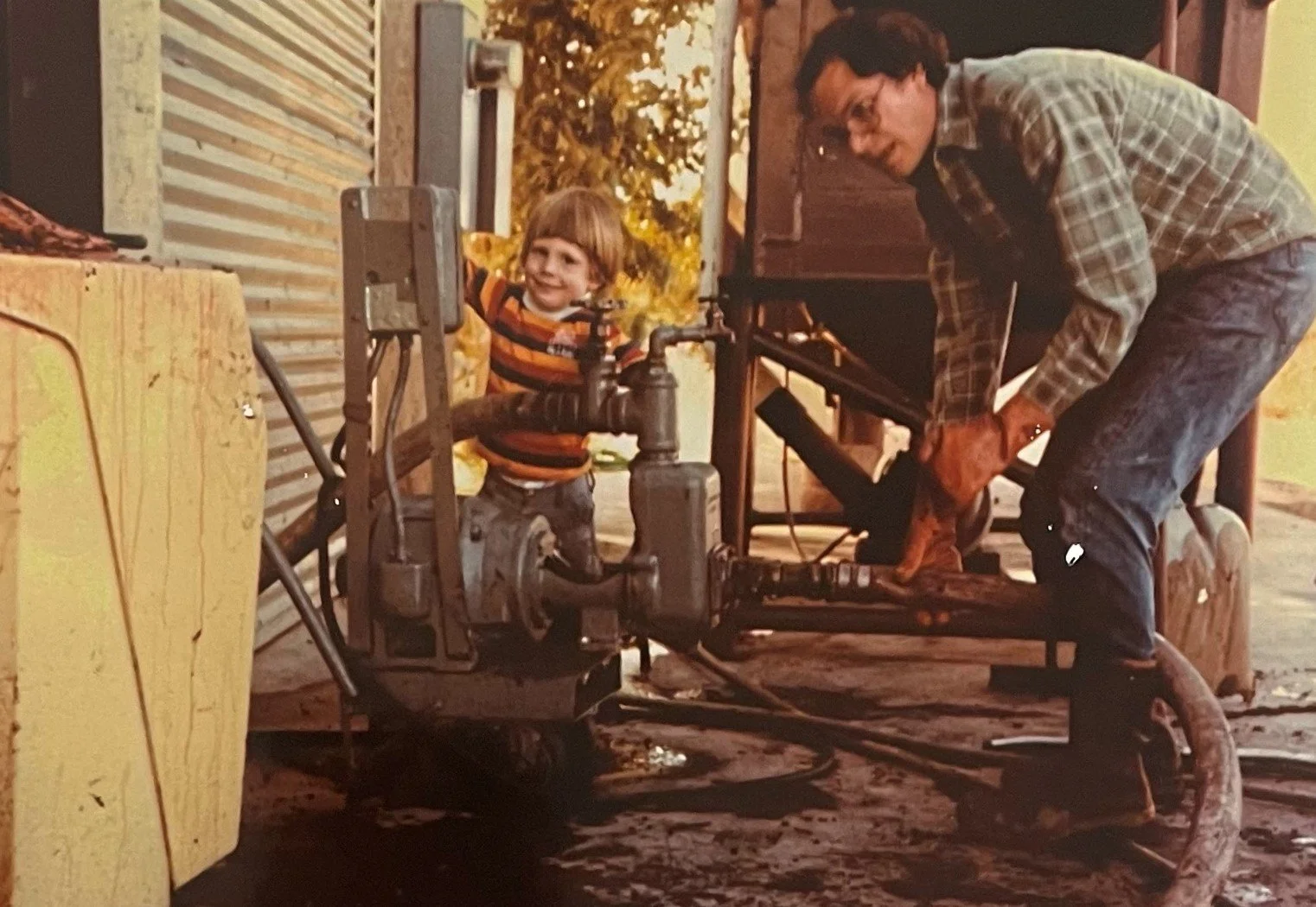 A photo of a very young Herb Quady and his father, Andy, operating a wine pump.