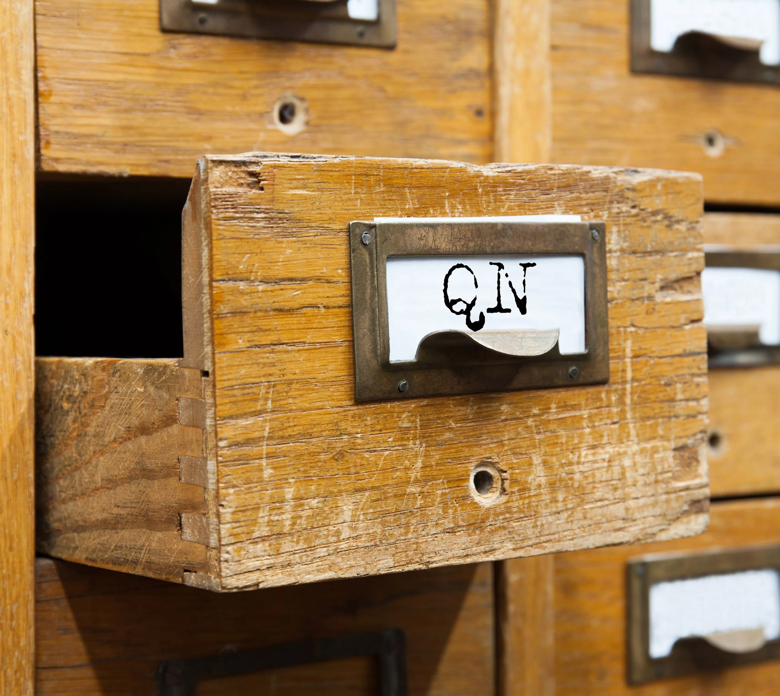 A photo of an old card catalog featuring a drawer with "QN" on the tab