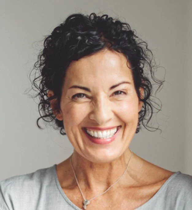 Women with brown curly tied up hair very happy after recieving Routine Hygienist treatment at Accent Your Dentists