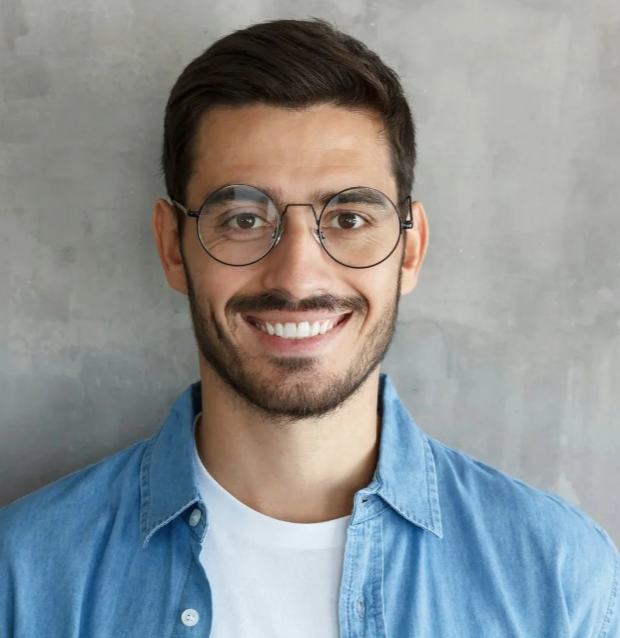 Young man with glasses smiling after restoring a damaged tooth with an inlay and onlay at Accent Your Dentist in Ponsonby, Auckland.