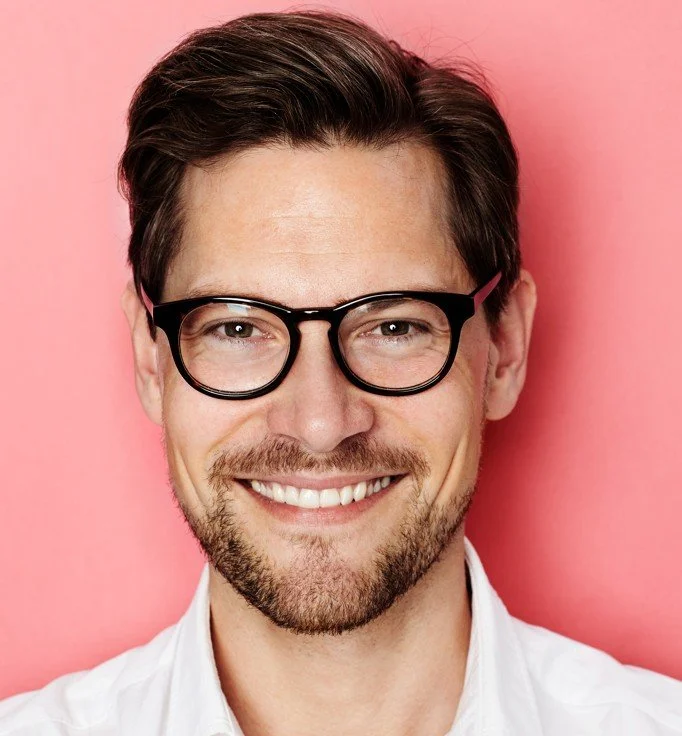 Man with glasses smiling after successful root canal treatment at Accent Your Dentist in Ponsonby, Auckland, preserving his natural tooth.