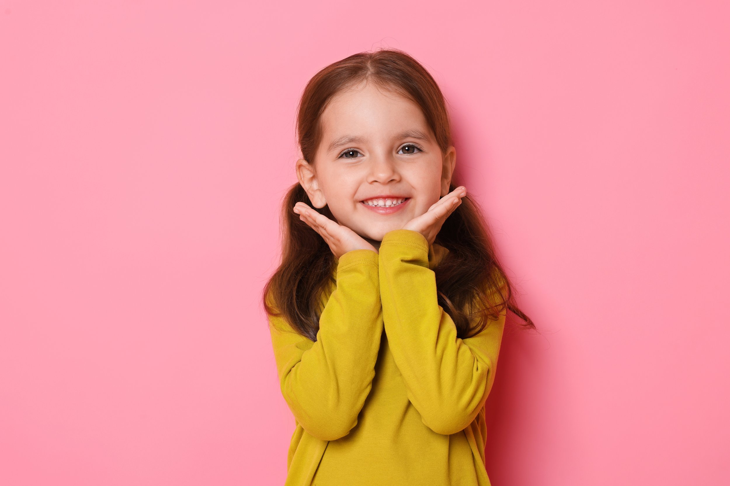 A young girl with brown hair, smiling, after receiving a children's checkup at Accent Your Dentists.