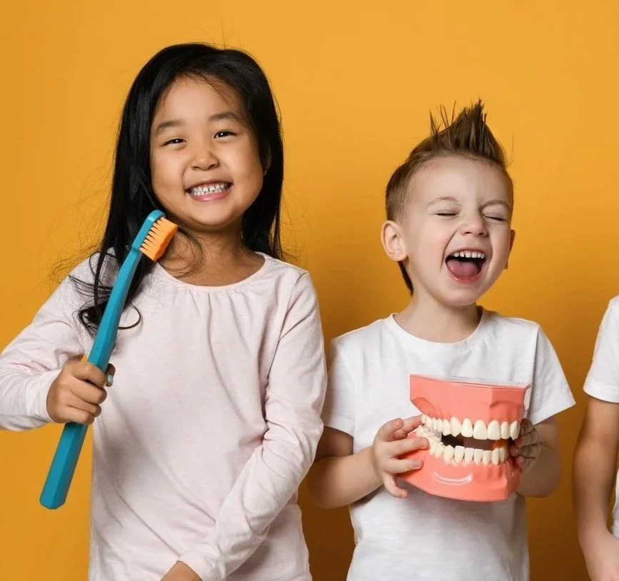 Two primary school children holding toothbrushes after visiting Accent Your Dentist in Ponsonby, Auckland for gentle children's dental care.