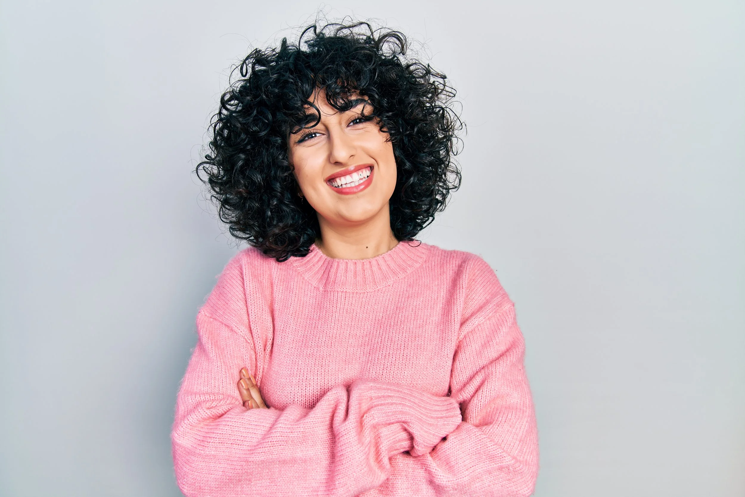 Arab woman in a pink jumper smiling at Accent Your Dentist in Ponsonby, Auckland, welcoming patients to personalised, comprehensive dental care.
