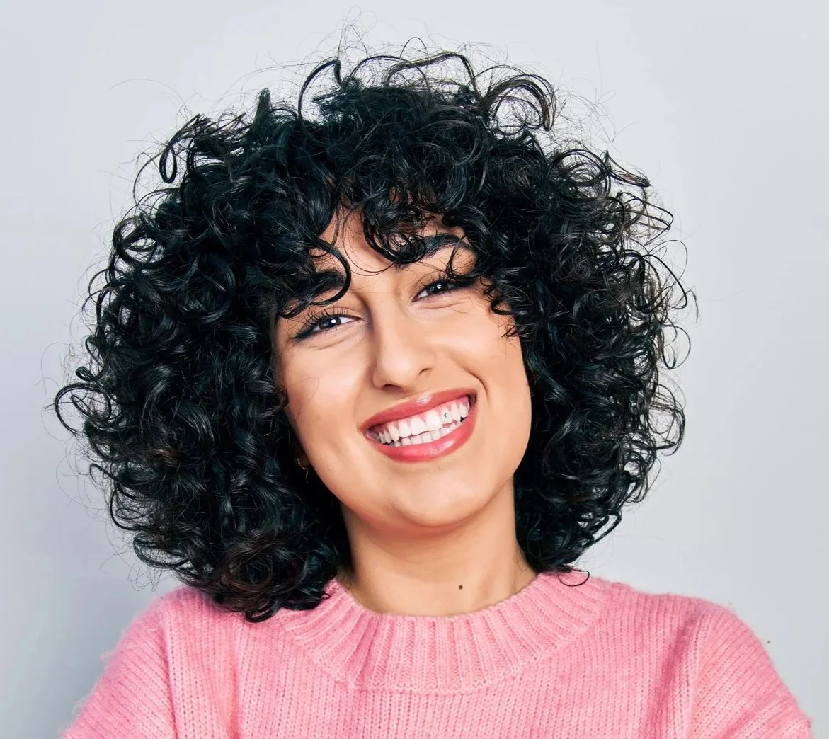 Woman with curly hair smiling after Smile You Love™ cosmetic dentistry at Accent Your Dentist in Ponsonby, Auckland.