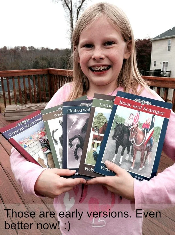 A young girl with braces smiling and holding several books about horses and riding outdoors on a wooden deck.
