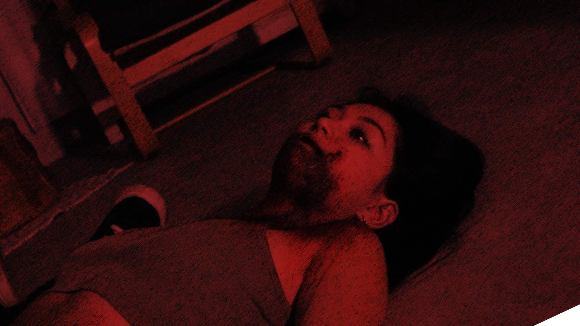 A woman lying on the floor looking up, with a red lighting effect.