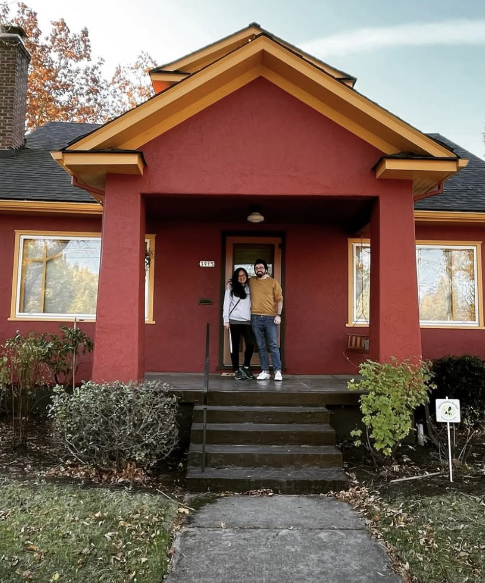 A couple standing on the front porch smiling for a photo, happily showing their successful homebuying process with Lou Chain.