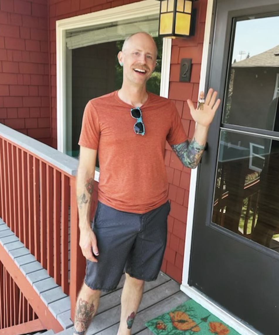 A smiling man in front of his new house that Realtor Lou Chain helped him find.