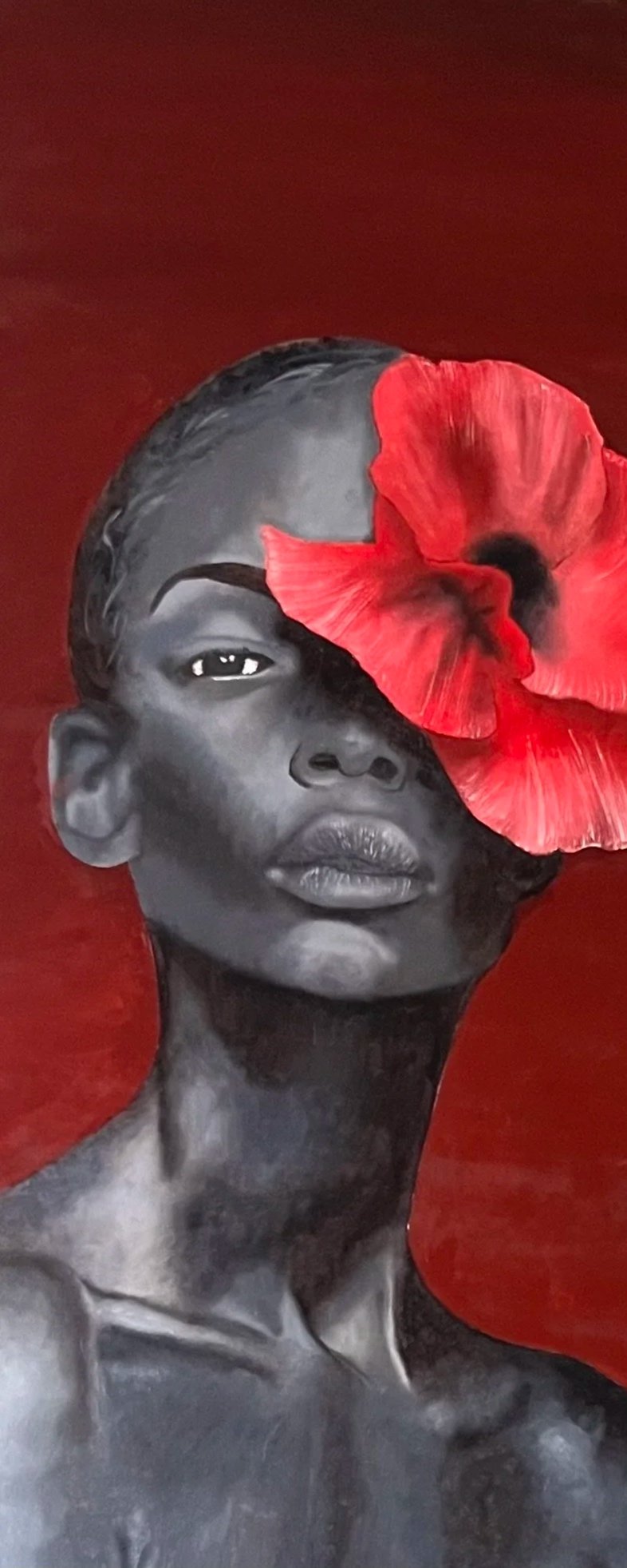 Black and white portrait of a young person with a red flower covering one eye, set against a red background.