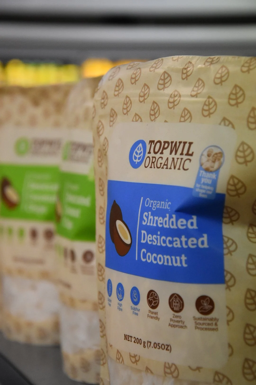 Packaged shredded desiccated coconut on a store shelf, branded Topwil Organic.