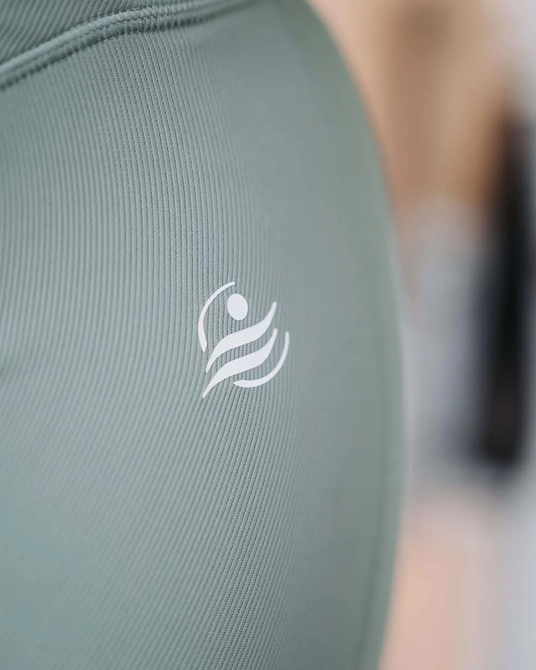 Close-up of a textured surface with a fitness or wellness logo featuring a stylized human figure with arms raised, on a green background.