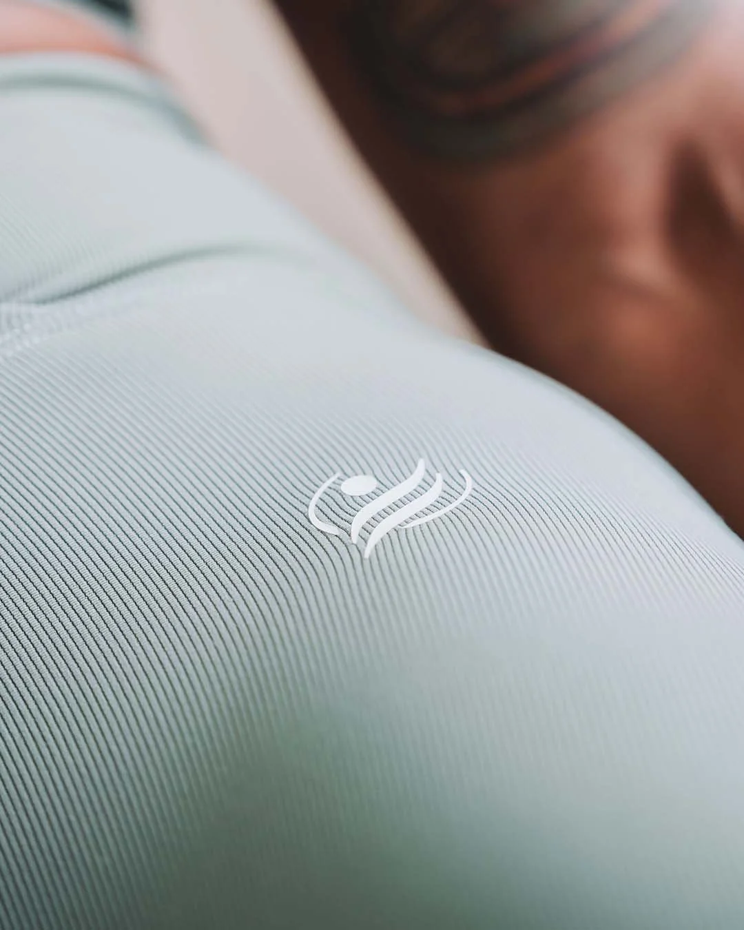 Close-up of a person sleeping with their head on a pillow, showing a white electronic device with a power symbol logo.