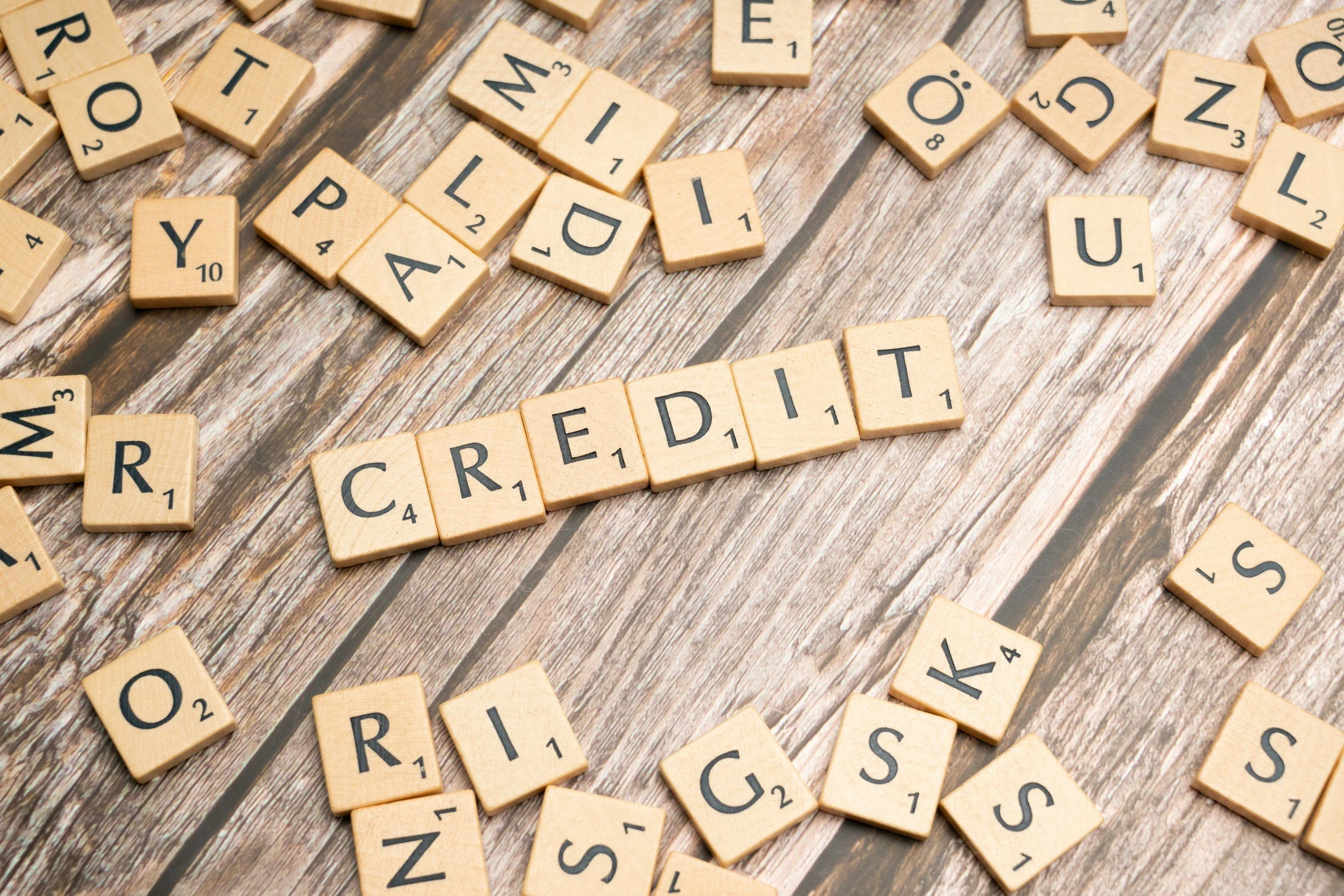 Scrabble tiles spelling out the word 'CREDIT' on a wooden surface.