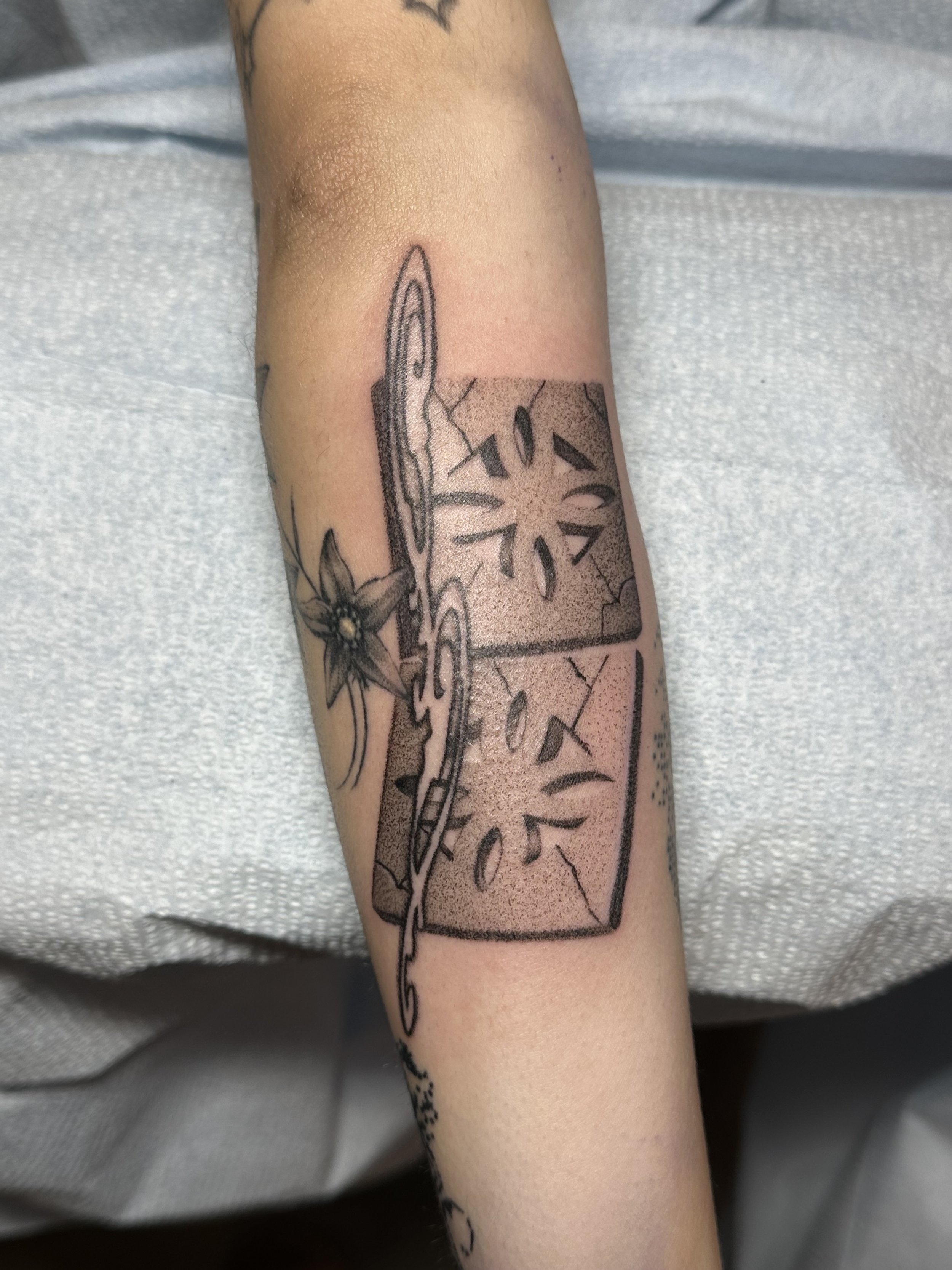 Tattoo of two mosaics with floral patterns, one with a star and other with a crescent, connected by a chain and a flower.