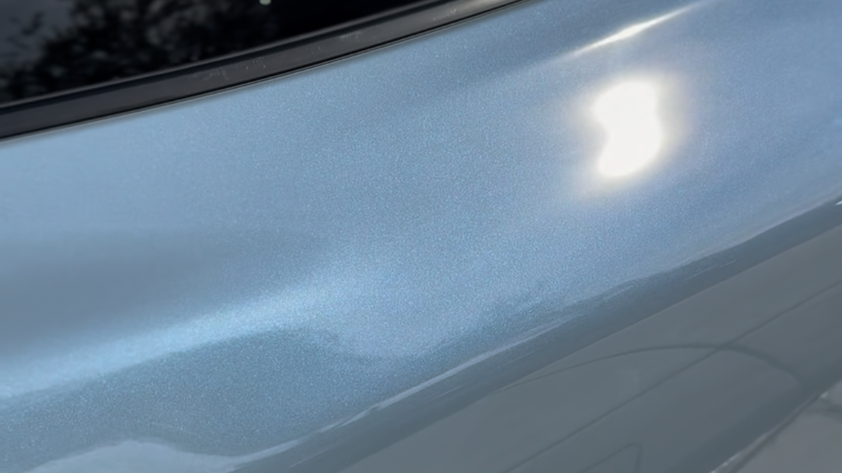 Close-up of metallic blue car exterior with sunlight reflection