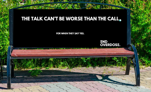 A park bench with an electronic sign displaying a message.