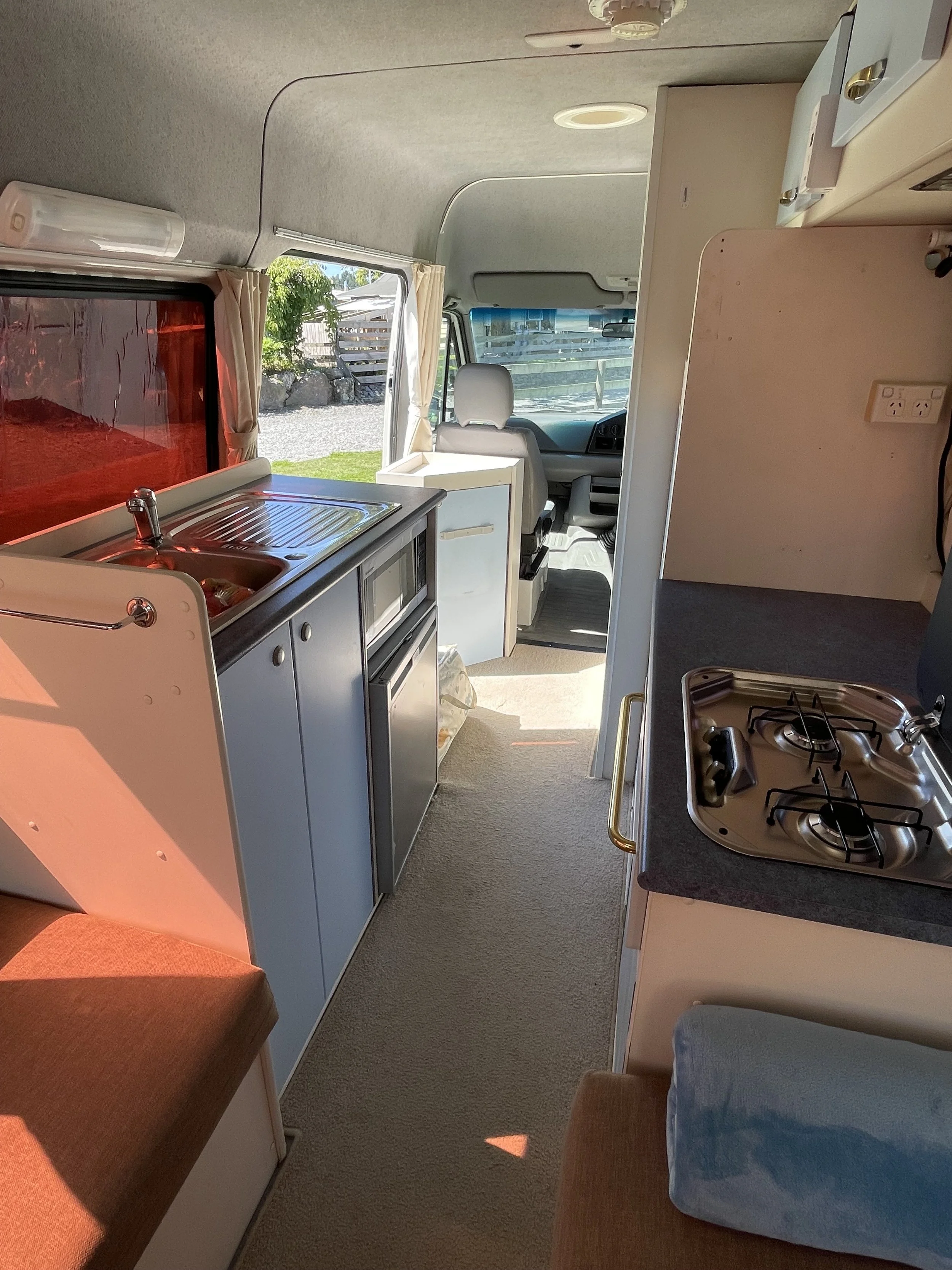 Kitchen countertop with a sink, a potted plant, a stove, and a refrigerator in a small kitchen