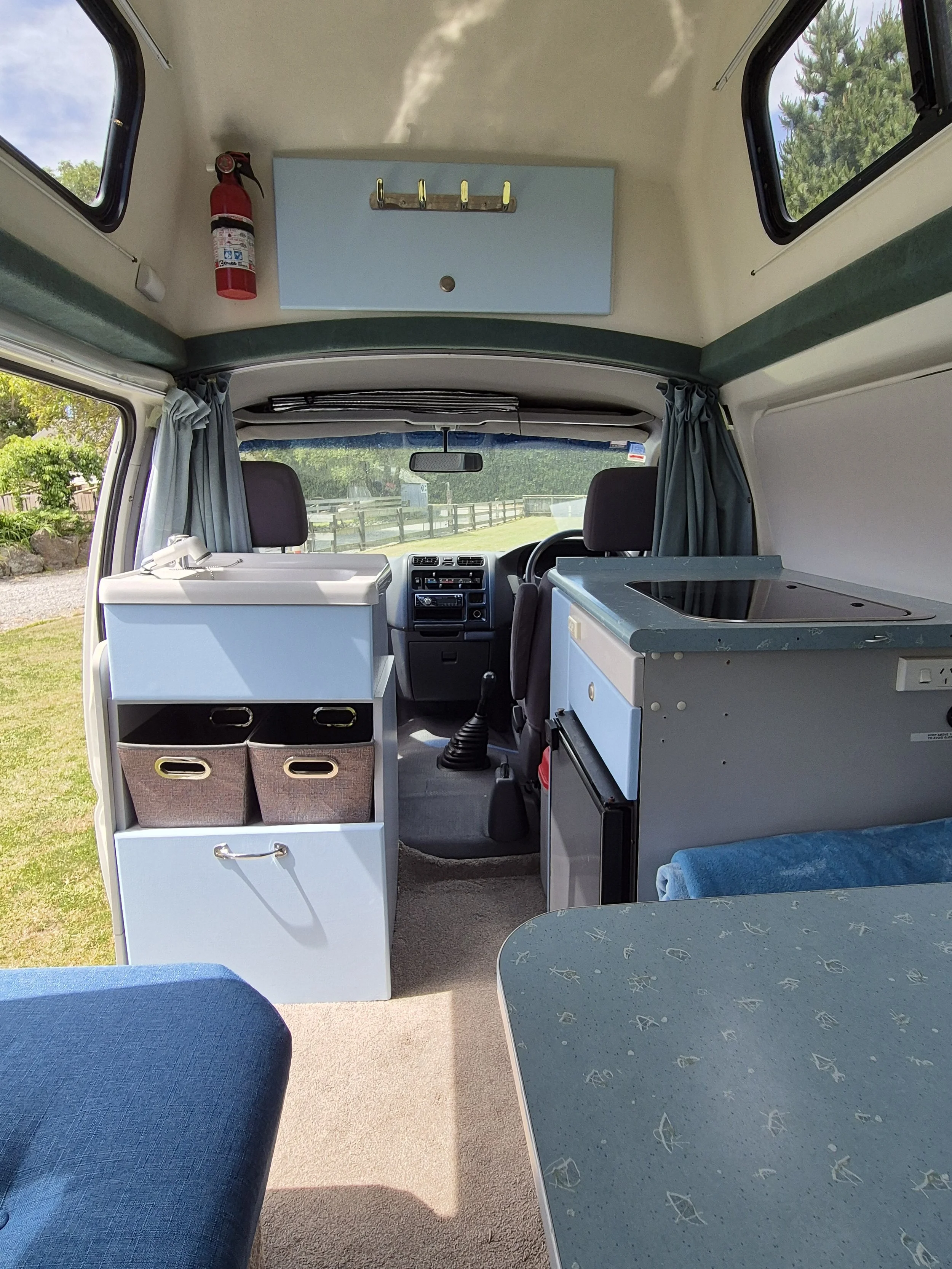 Kitchen countertop with a sink, a potted plant, a stove, and a refrigerator in a small kitchen
