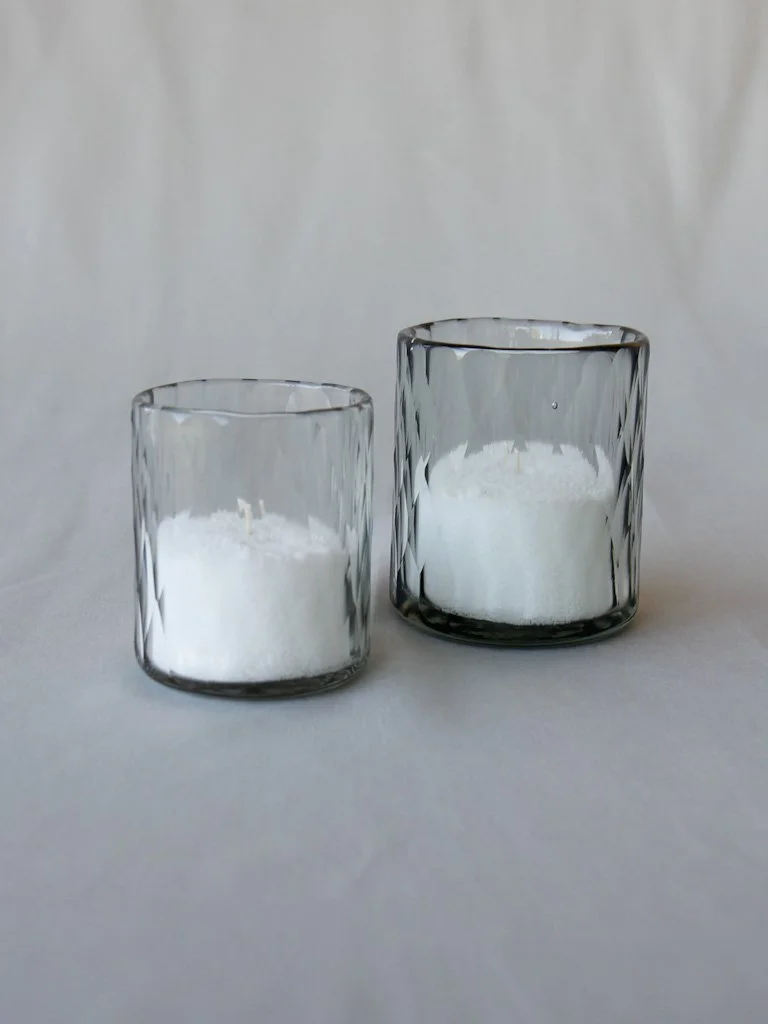 Two clear glass containers with white powder, one smaller and one larger, against a plain background.