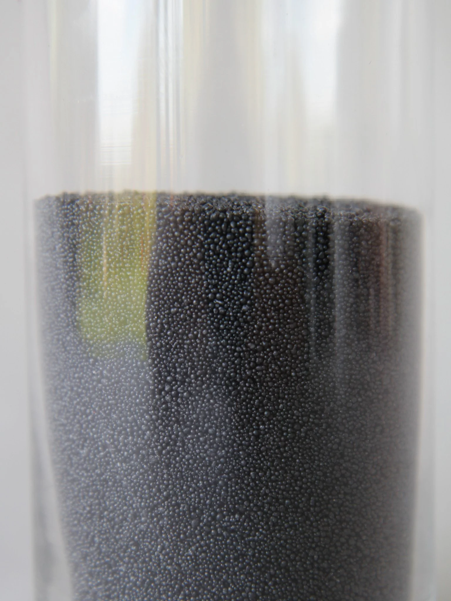 Close-up of a glass container filled with tiny black beads.