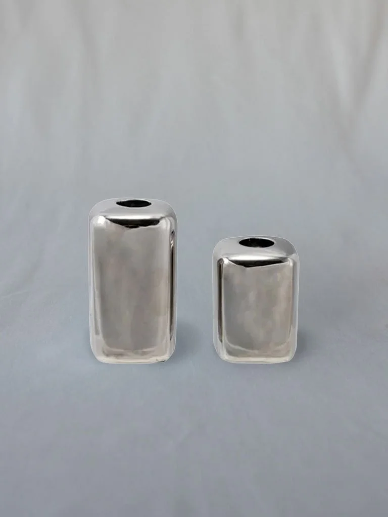 Two metallic vases of different heights, silver in color, on a neutral background.
