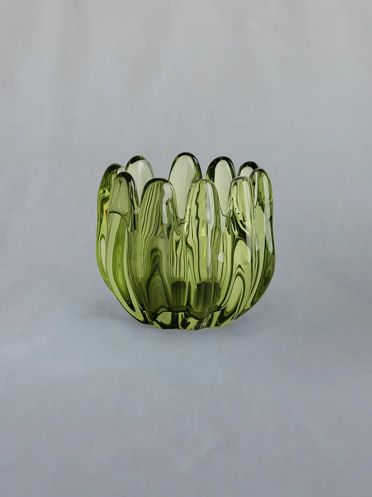 A green glass vase with a wavy, ribbed design, set against a plain light gray background.