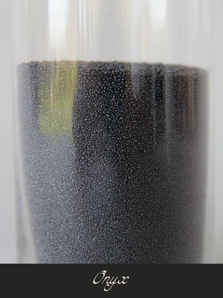 Close-up view of a transparent glass filled with black caviar, with the word 'Onyx' written at the bottom.