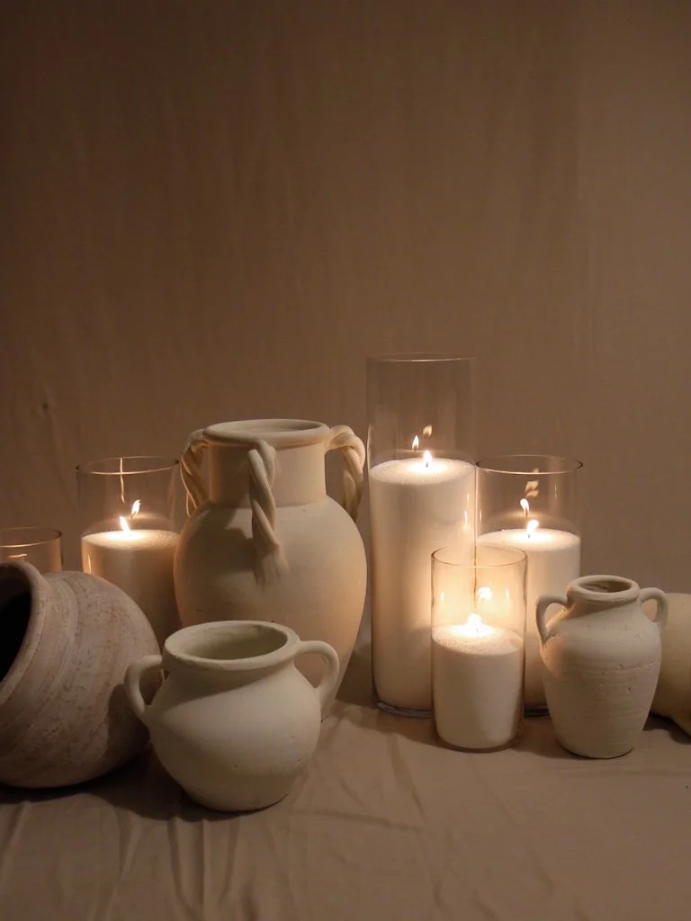 Ceramic vessels and lit candles on a table, creating a warm, cozy ambiance.