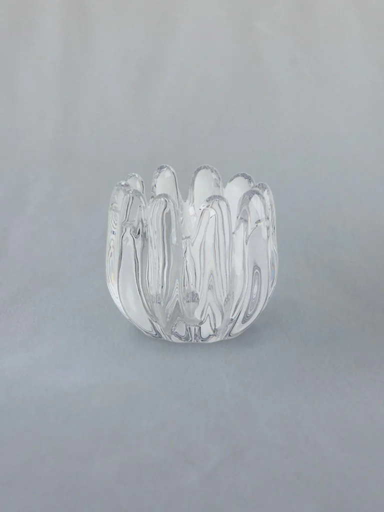 Clear glass vase with a wavy, textured surface, placed on a plain gray background.