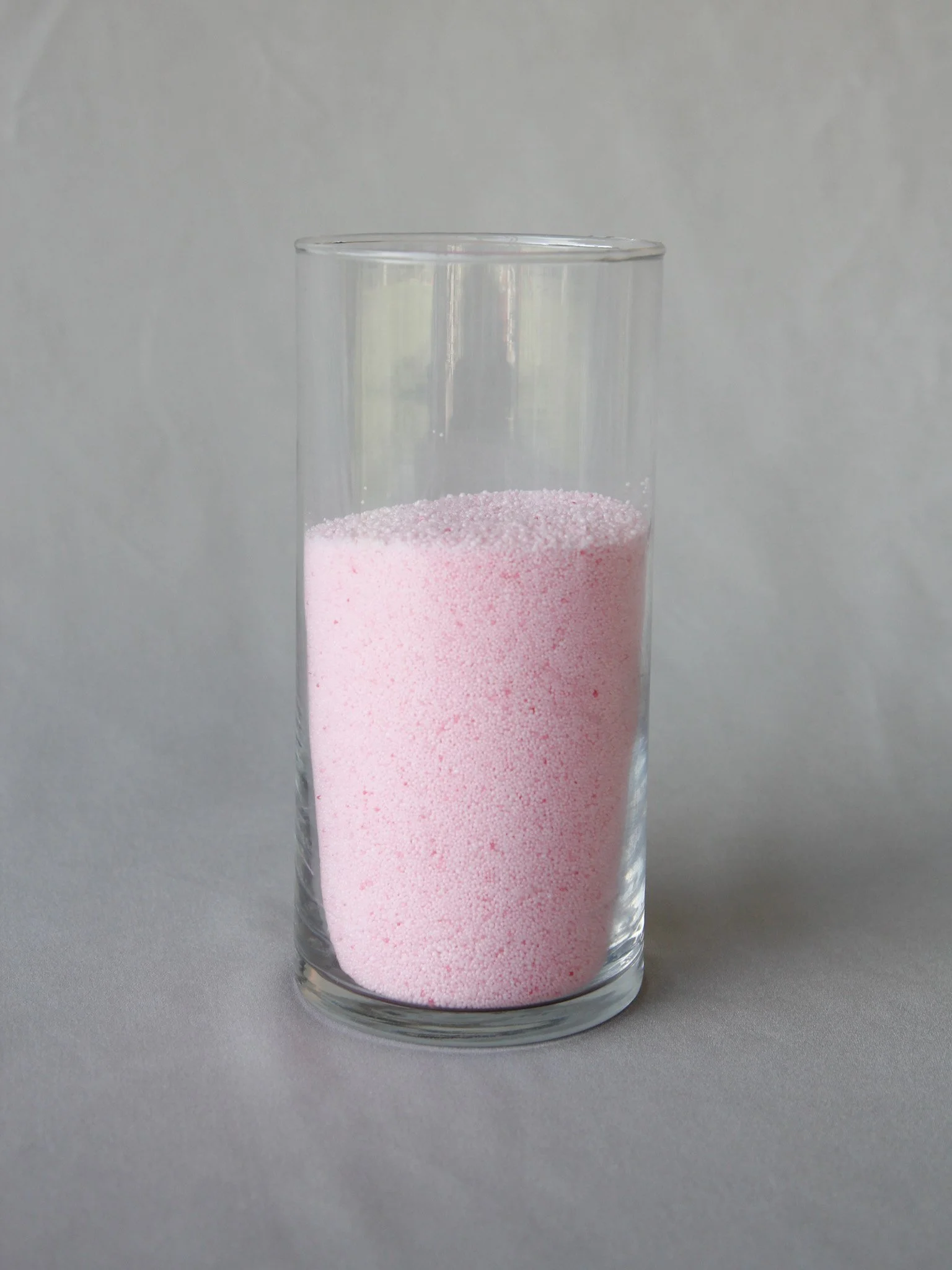 A clear glass filled with pink bubble bath liquid.