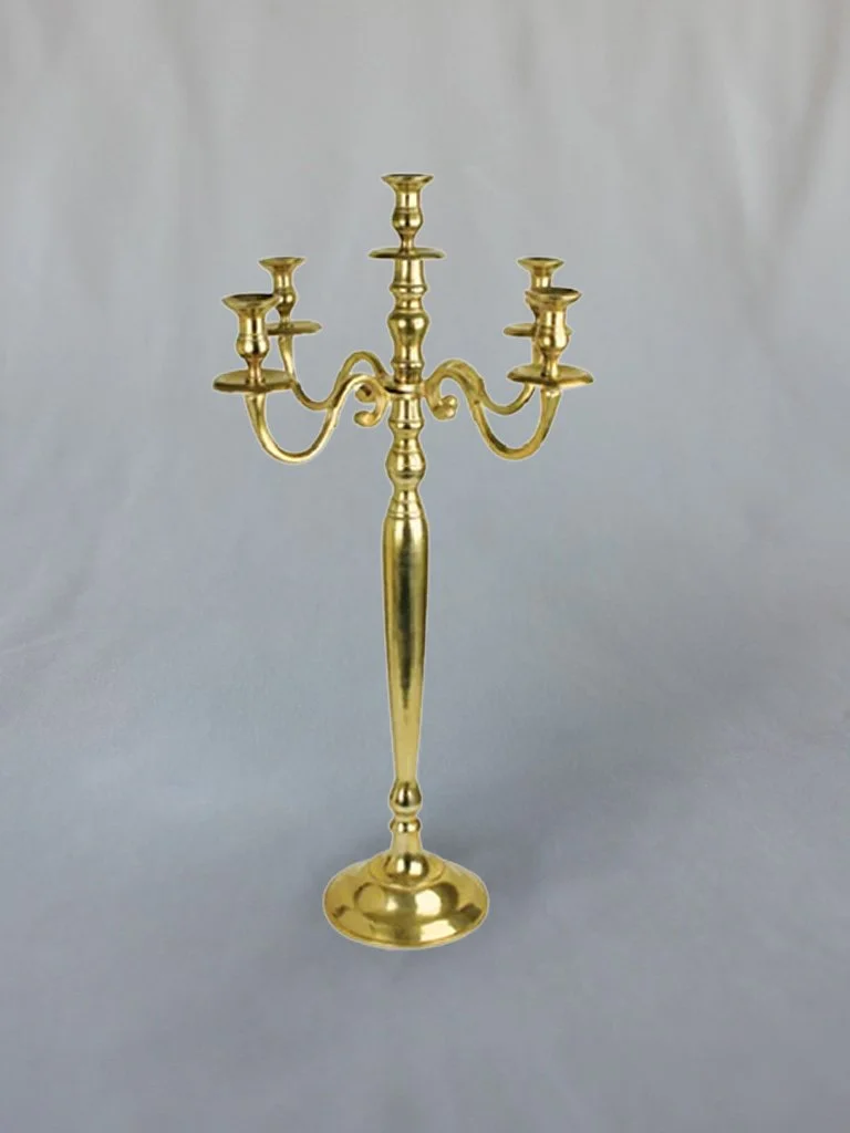 A gold-colored candelabrum with five candle holders, standing against a plain gray background.