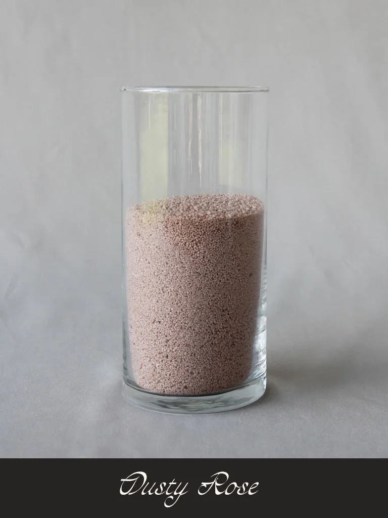 A tall clear glass filled with small pink granular beads labeled 'Dusty Rose' at the bottom.