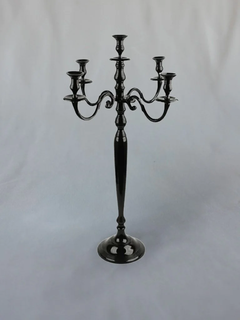 Black metal candelabra with five candle holders, centered against a plain light-colored background.