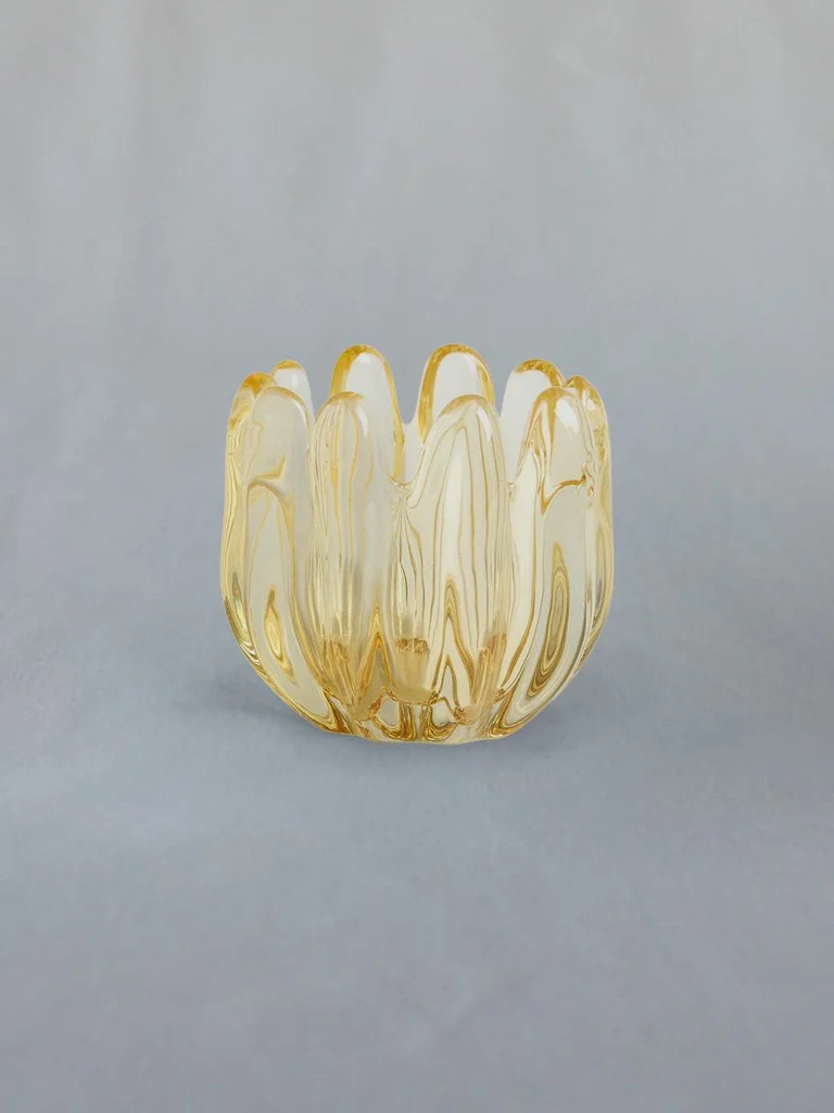 A decorative glass vase with a petal-like design, yellow and clear swirl pattern, on a plain gray background.