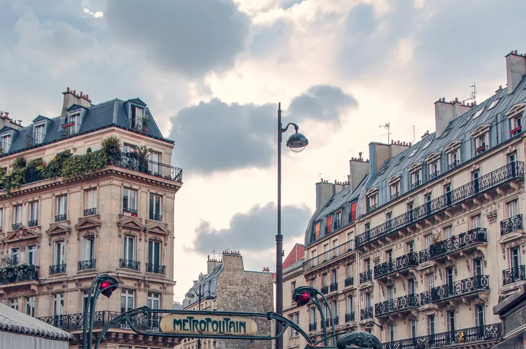 Parisian street scene with classic Haussmann-style buildings, street lamps, and a sign for the Métropolitain metro station.